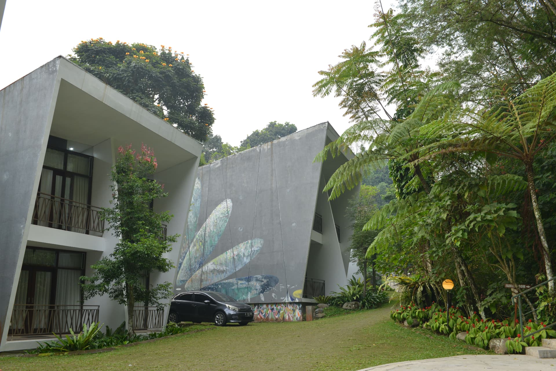 Angular concrete villa block with mural facade and garden lawn